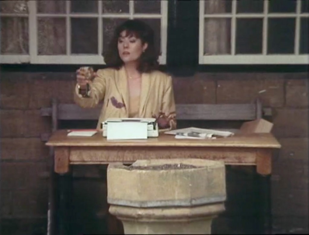 Sarah Jane drinking white wine whilst typing outside a Cotswold country pub